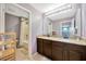Bathroom with granite countertop, dual sinks, wood cabinets, and a view of the shower/tub at 5624 Fisher Glen Loop, Wesley Chapel, FL 33545