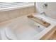 A luxurious white bathtub features a stylish wooden tray, perfect for relaxation at 5624 Fisher Glen Loop, Wesley Chapel, FL 33545