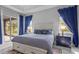 Bright bedroom featuring a white bed frame, blue accents and curtains, and access to outdoor patio at 5742 Stockport St, Riverview, FL 33578