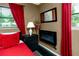 Cozy bedroom with an electric fireplace, red curtains, and a side table with lamp, creating a warm atmosphere at 614 12Th Nw St, Largo, FL 33770