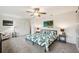 Bright primary bedroom with a ceiling fan, palm tree artwork, and neutral carpeting at 6913 Grande Vista S Way, St Petersburg, FL 33707