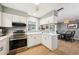 Well-lit kitchen featuring white cabinetry, stainless steel appliances, and an adjacent dining area at 6913 Grande Vista S Way, St Petersburg, FL 33707