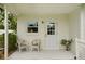 Charming covered patio with matching white wicker furniture and a view of the yard at 6913 Grande Vista S Way, St Petersburg, FL 33707
