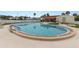 Community pool area featuring clear blue water, a lounge area, and beautiful landscaping at 7118 El Meyers St, Zephyrhills, FL 33541