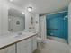 Bathroom featuring a blue-tiled shower, a white vanity, and floral wallpaper at 7600 Sun Island S Dr # 603, South Pasadena, FL 33707