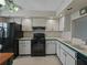 Small kitchen with white cabinets and black appliances; black range and black refrigerator at 7600 Sun Island S Dr # 603, South Pasadena, FL 33707