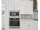 This modern kitchen features built-in stainless steel microwave and oven with white cabinets and stylish mosaic backsplash at 8316 Golden Beach Ct, Parrish, FL 34219