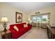 The living room, bathed in sunlight, features hardwood floors and a comfortable red sofa at 960 Virginia St # 202, Dunedin, FL 34698