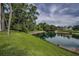 Lush lawn sloping toward serene pond with tree line on opposite bank at 960 Virginia St # 202, Dunedin, FL 34698