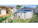 This photo displays the pool in a fenced-in backyard, with a ladder for access and an umbrella for shade at 9892 111Th St, Seminole, FL 33772