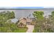 An aerial view captures the home's waterfront location, mature trees, and circular driveway at 115 Lake Shore E Dr, Palm Harbor, FL 34684
