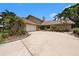 Charming home features a two-car garage, mature landscaping, and a colorful front door at 115 Lake Shore E Dr, Palm Harbor, FL 34684