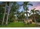 Charming single-story home featuring tropical landscaping and a well-manicured lawn under a picturesque sky at 1151 Lancer Ln, Tarpon Springs, FL 34689