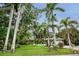 Charming single-story home featuring tropical landscaping and a well-manicured lawn under a beautiful blue sky at 1151 Lancer Ln, Tarpon Springs, FL 34689