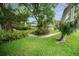 Beautifully landscaped front yard with lush green lawn and mature trees at 1151 Lancer Ln, Tarpon Springs, FL 34689