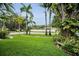Well-manicured front yard featuring green lawn, palm trees, and a mosaic bench, creating a welcoming curb appeal at 1151 Lancer Ln, Tarpon Springs, FL 34689