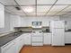 Compact kitchen with white appliances, ample counter space, and laminate wood flooring at 13500 Gulf Blvd # 507, Madeira Beach, FL 33708