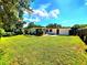 Expansive backyard with lush green lawn, patio area, and the home's exterior under a sunny sky at 1373 Fairfax Rd, Clearwater, FL 33764