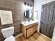 Modern bathroom featuring updated vanity, lighting, wood accent wall, updated flooring, and updated toilet at 1373 Fairfax Rd, Clearwater, FL 33764