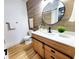 Modern bathroom featuring updated vanity, lighting, wood accent wall, updated flooring, and updated toilet at 1373 Fairfax Rd, Clearwater, FL 33764