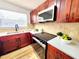 Modern kitchen featuring updated appliances, stone countertops, and cherry wood cabinets at 1373 Fairfax Rd, Clearwater, FL 33764