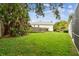 Large grassy backyard featuring partial views of the home, with trees and a wooden fence at 16003 Ridley Pl, Tampa, FL 33647