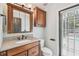 Bathroom with wooden vanity, granite countertop, decorative mirror, and a window with backyard pool view at 16003 Ridley Pl, Tampa, FL 33647