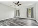 Spacious bedroom with gray wood-look flooring, neutral walls, ceiling fan and two windows with gray curtains at 16003 Ridley Pl, Tampa, FL 33647