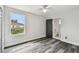 Bedroom with gray wood floors, ceiling fan, large window, and bathroom access at 16003 Ridley Pl, Tampa, FL 33647