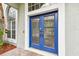 Stylish blue front door with decorative glass panels, complemented by brick accents and natural light at 16003 Ridley Pl, Tampa, FL 33647