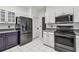 Updated kitchen features stainless steel appliances, white cabinets, grey countertops, and white tile flooring at 16003 Ridley Pl, Tampa, FL 33647