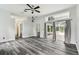 Open living room featuring gray plank flooring, a ceiling fan, and sliding glass doors to the outdoor living space at 16003 Ridley Pl, Tampa, FL 33647