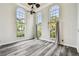Bright living room with gray wood floors, tall arch windows, and modern ceiling fan at 16003 Ridley Pl, Tampa, FL 33647