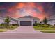Charming single-story home featuring manicured landscaping, a gray two-car garage door, and a paver driveway at 16126 San Donato Pl, Bradenton, FL 34211