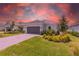 Charming single-story home featuring manicured landscaping, a gray two-car garage door, and a paver driveway at 16126 San Donato Pl, Bradenton, FL 34211