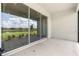Covered patio with tranquil view of the pond, expansive lawns, and neighboring houses reflected in sliding glass doors at 16126 San Donato Pl, Bradenton, FL 34211