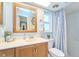 Bathroom featuring a wooden vanity, window, shower with blue curtain, and decorative accessories at 2273 Willowbrook Dr, Clearwater, FL 33764