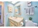 Bright bathroom with a decorative mirror, cream vanity, neutral countertops, and sky blue walls at 2273 Willowbrook Dr, Clearwater, FL 33764