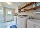 Bright laundry room featuring a utility sink, modern washer and dryer, and convenient shelving at 2273 Willowbrook Dr, Clearwater, FL 33764