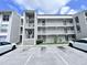 Condominium building with white facade, outdoor stairwell, and parking lot in front at 2625 State Road 590 # 1012, Clearwater, FL 33759