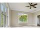 Bright bedroom with tile flooring, a ceiling fan, and a large window with views of lush greenery at 2708 Coastal Range Way, Lutz, FL 33559