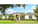 Beautiful home showcasing a manicured lawn, mature trees, and an elegant, arched entryway at 2708 Coastal Range Way, Lutz, FL 33559