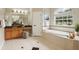 Bright bathroom features a soaking tub, walk-in shower, wood cabinetry, and a large window at 2708 Coastal Range Way, Lutz, FL 33559