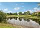 Picturesque pond view reflecting the sky with mature trees and the serene backdrop of a neighborhood at 2708 Coastal Range Way, Lutz, FL 33559