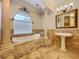 Elegant bathroom featuring a soaking tub, pedestal sink, walk-in shower and decorative wall mirror at 27511 Hialeah Way, Wesley Chapel, FL 33544