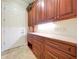 Traditional butlery featuring ample cherry wood cabinetry, granite counters, and a white service door at 27511 Hialeah Way, Wesley Chapel, FL 33544