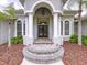 A stunning front entrance with elegant columns, a grand arched doorway, and meticulously maintained landscaping at 27511 Hialeah Way, Wesley Chapel, FL 33544