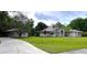 A single-story home with a lush green lawn, a side-entry garage, and mature trees in the background at 27511 Hialeah Way, Wesley Chapel, FL 33544