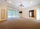Expansive living room features large glass doors to the lanai, neutral carpet, and modern ceiling fan at 27511 Hialeah Way, Wesley Chapel, FL 33544