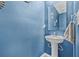 Stylish powder room featuring a pedestal sink, modern mirror, and vibrant blue walls at 2771 Suncoast Blend Dr, Odessa, FL 33556